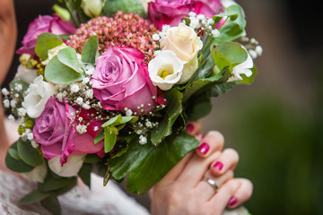 hand with red nails are holidng the bridals bouquet
