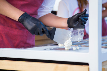 Chef cooking handmade natural asian stir-fried ice cream at freeze pan. Outdoor cooking, gastronomy and street food festival concept