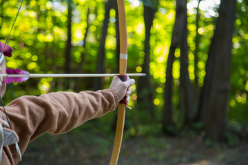 Medieval male archer shooting targets with wooden bow at historical festival - close up shot....