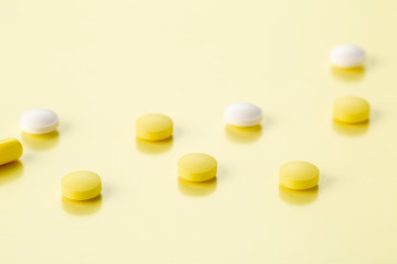 various round tablets and capsules with antibiotics on a yellow background