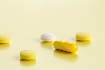 various round tablets and capsules with antibiotics on a yellow background