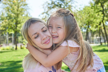 little girl hugs mom in the park