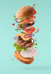 Delicious burger with flying ingredients isolated .