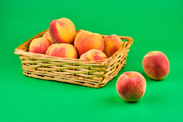 Peach fruit in basket on green background