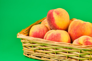 Peach fruit in basket on green background