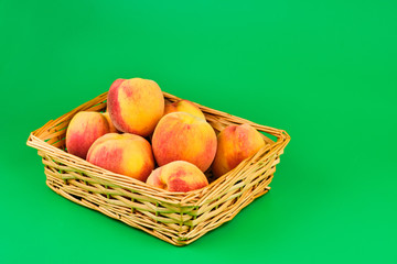 Peach fruit in basket on green background