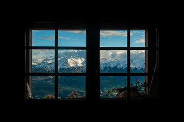 Snowy mountains framed by alpine hut window