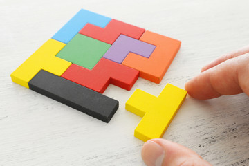 business concept image of a colorful square tangram puzzle, over wooden table