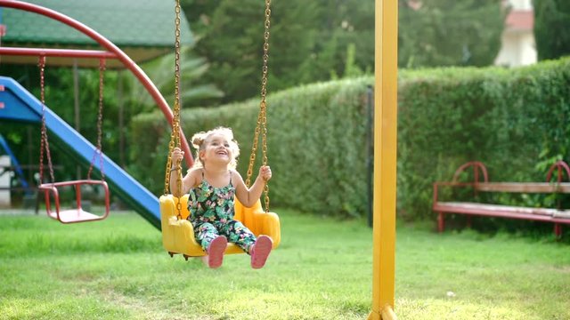 Happy little girl on a swing in the park