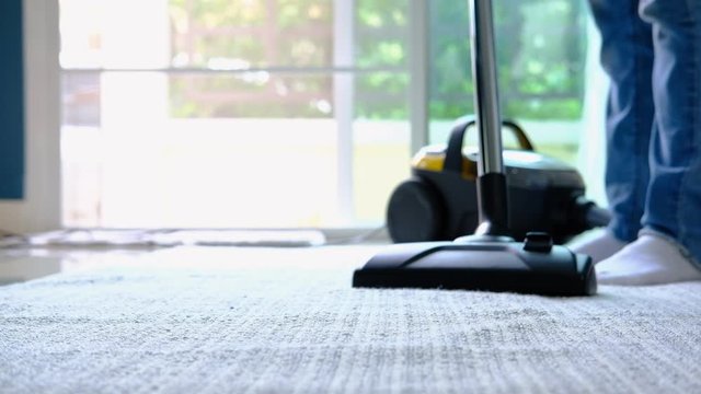 Young woman cleaning the carpet with vacuum cleaner in living room, Housework concept