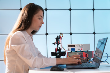 A young woman writes an algorithm for the robot arm. Science Research Laboratory for Robotic Arm...
