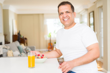Middle age arab man eating cereals at breakfast with happy face