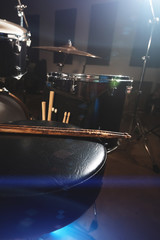 Close-up of used drumsticks lie on a drummer's chair against the background of a drum kit and flare of spotlights. The concept of music