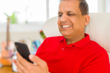 Middle age man smiling cheerful white using smartphone sitting on the sofa at home