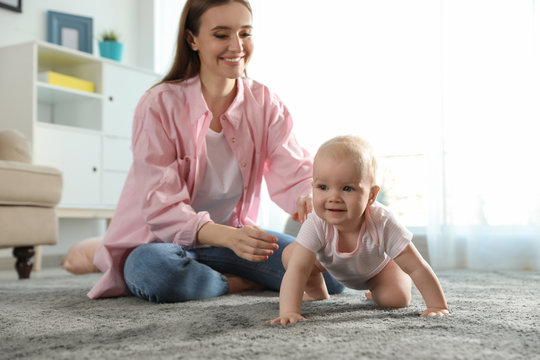 Adorable little baby crawling near mother at home