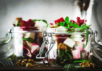 Beet and cheese healthy salad with arugula and walnuts, trendy salad jar, gray kitchen table, place for text, selective focus