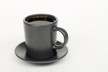 Dark cup of coffee on a white background. Espresso in a dark cup on the left.
