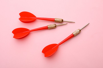 Red dart arrows on pink background, flat lay