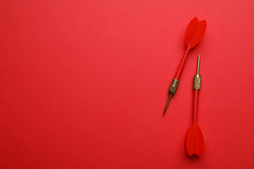 Plastic dart arrows on red background, flat lay with space for text