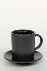 Dark cup of coffee on a white background. Espresso in a dark cup in the center