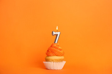 Birthday cupcake with number seven candle on orange background