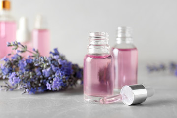 Fototapeta na wymiar Bottles of essential oil and lavender flowers on stone table