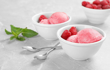 Bowls with delicious raspberry ice cream on grey marble table