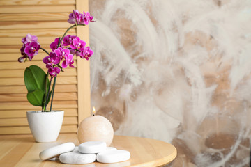 Spa stones, candle and blooming orchid indoors, space for text