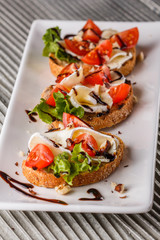 Bruschetta with tomatoes, lettuce, camambert, balsamic vinegar