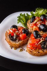 Italian bruschetta with tomato, black olives, lettuce and mustard