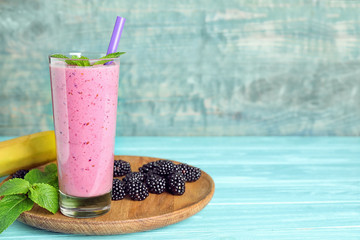 Delicious blackberry smoothie in glass served on light blue wooden table. Space for text