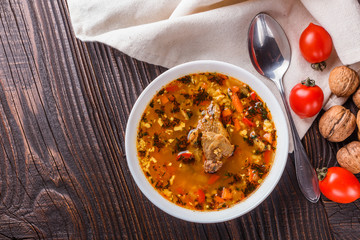 Georgian soup. Kharcho with rice, tomato, beef, garlic and herbs in bowl on wooden table