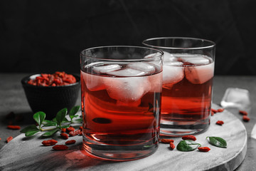 Healthy goji juice with ice in glasses on table