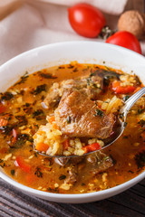 Georgian soup. Kharcho with rice, tomato, beef, garlic and herbs in bowl on wooden table