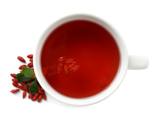 Healthy goji tea in cup with berries on white background, top view