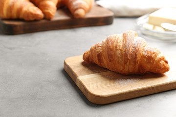 Wooden board with tasty croissant and space for text on grey table. French pastry