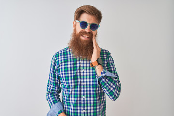 Naklejka premium Young redhead irish man wearing casual shirt and sunglasses over isolated white background touching mouth with hand with painful expression because of toothache or dental illness on teeth.