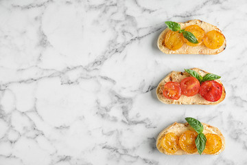 Delicious tomato bruschettas on white marble background, flat lay. Space for text
