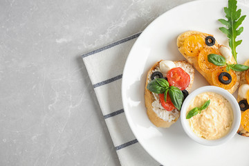 Plate of delicious tomato bruschettas on light grey marble background, top view. Space for text