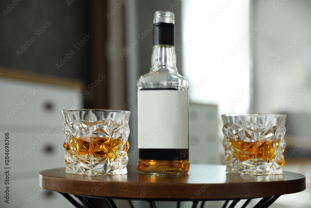 Wall mural Glasses and bottle of whiskey on table indoors