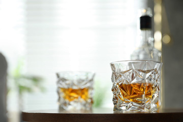 Glasses and bottle of whiskey on table indoors. Space for text