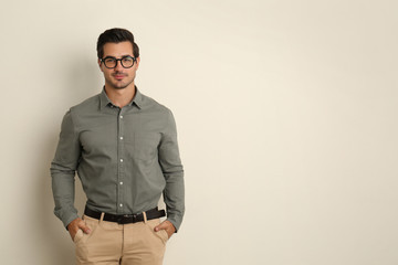 Fototapeta premium Young male teacher with glasses on beige background. Space for text