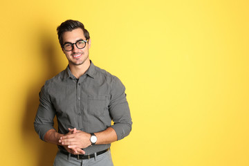 Young man with glasses on yellow background. Space for text