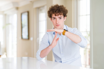 Young business man with curly read head Doing time out gesture with hands, frustrated and serious...
