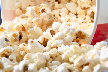 Striped paper cup with popcorn. Tasty popcorn background. Snack for a movie, an idea for a meal. Close-up, top view. Copy space for text.
