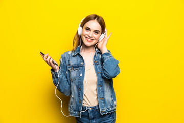 Happy cheerful woman wearing headphones listening to music from smartphone studio shot isolated on...
