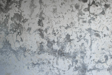 A gray concrete wall with a vertical lighting gradient interspersed with white plaster and paint. Background