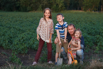 Three children with his father having fun in the field. The concept of the beginning of construction of the future house, the revival of agriculture, a friendly family.
