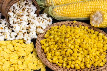 Corn cobs, grains of corn in a wicker plate, popcorn and flakes.