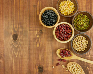 Flat lay,top view assorted beans including red bean,soybeans,black beans,mung beans on brown,beige wooden background with copy space 
